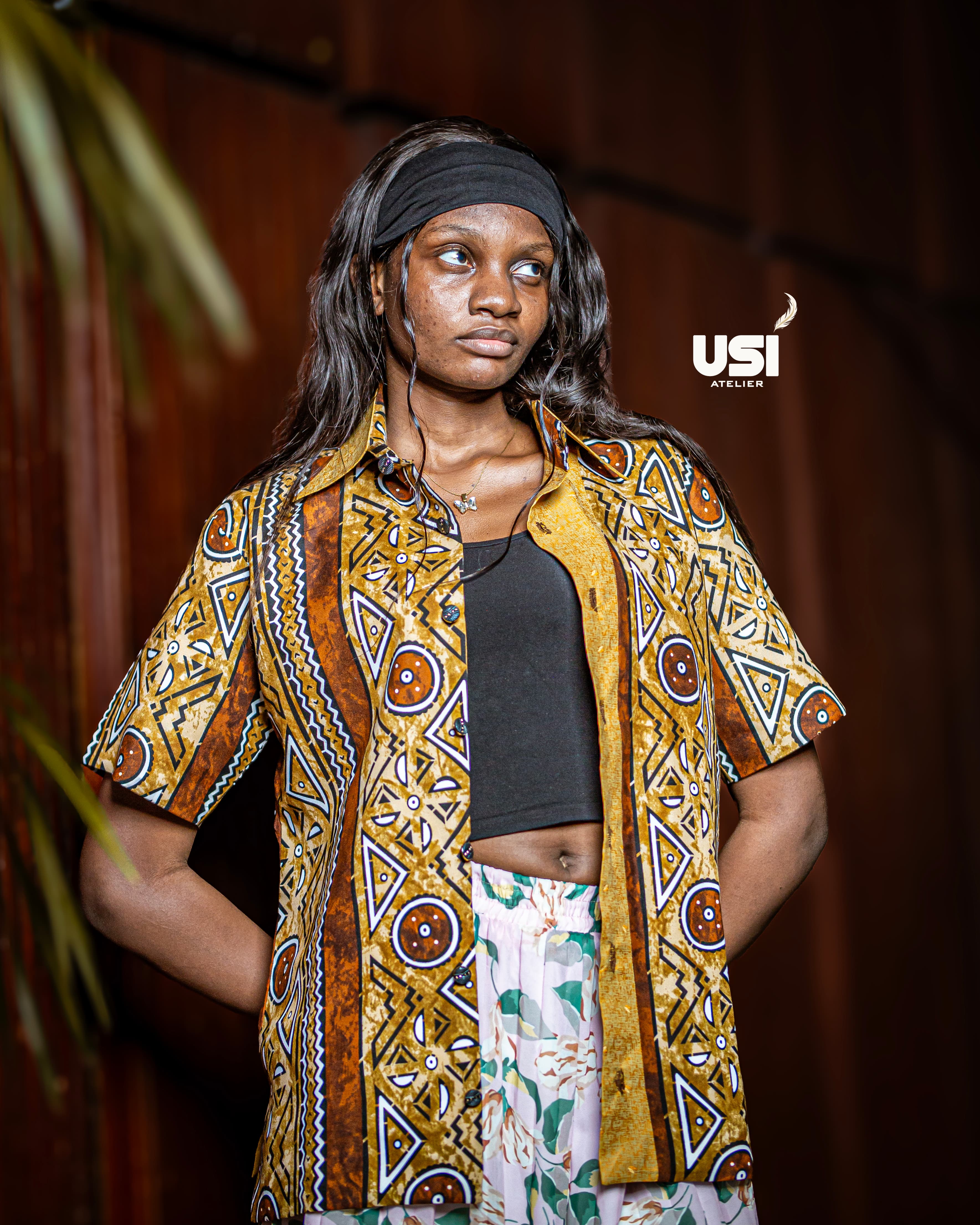 A model wearing a patterned short-sleeve shirt over a black top